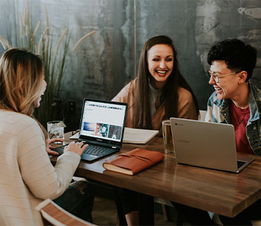 Three people around a table with a computer